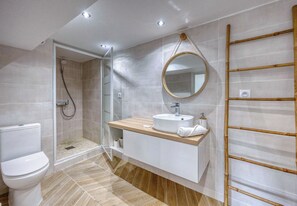 A modern bathroom with a toilet, shower, vanity with a sink, and a mirror.