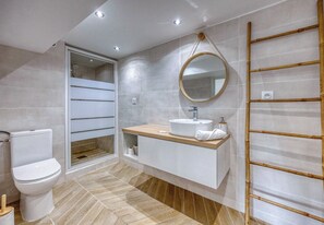 Une salle de bain moderne comprenant des toilettes, un lavabo avec un miroir et un espace douche.