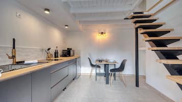 Una cucina moderna con isola centrale, zona pranzo con tavolo e sedie, e una scala in legno.