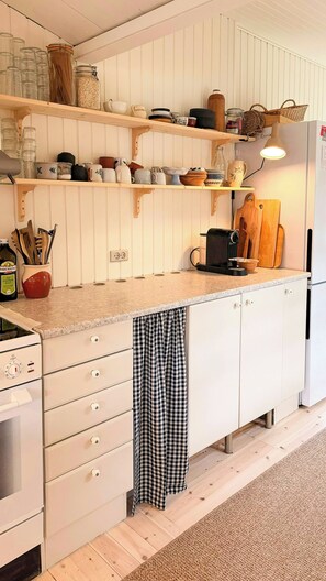 Een keuken met witte kasten, een houten aanrecht en diverse keukengerei.