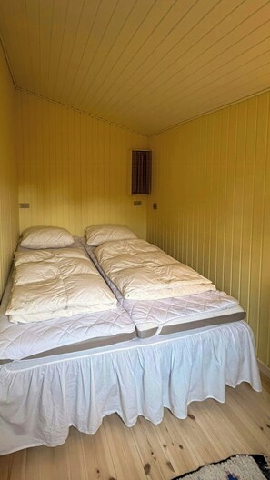 Ein Einzelbett in einem Zimmer mit gelben Wänden und Holzboden.