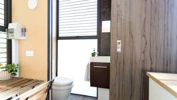 Un baño pequeño con inodoro, lavamanos y un ventanal.