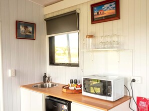 A compact kitchen with a microwave, sink, and a window above the counter.