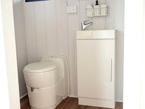 A small, white bathroom with a toilet, a sink, and a cabinet.