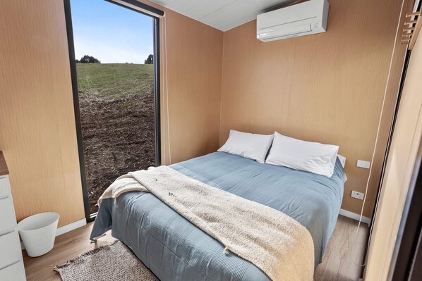 Un dormitorio con cama, ventana y aire acondicionado.