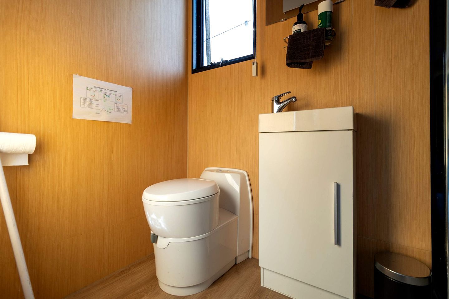 Ein kleines Badezimmer mit Toilette, Schrank und Fenster.