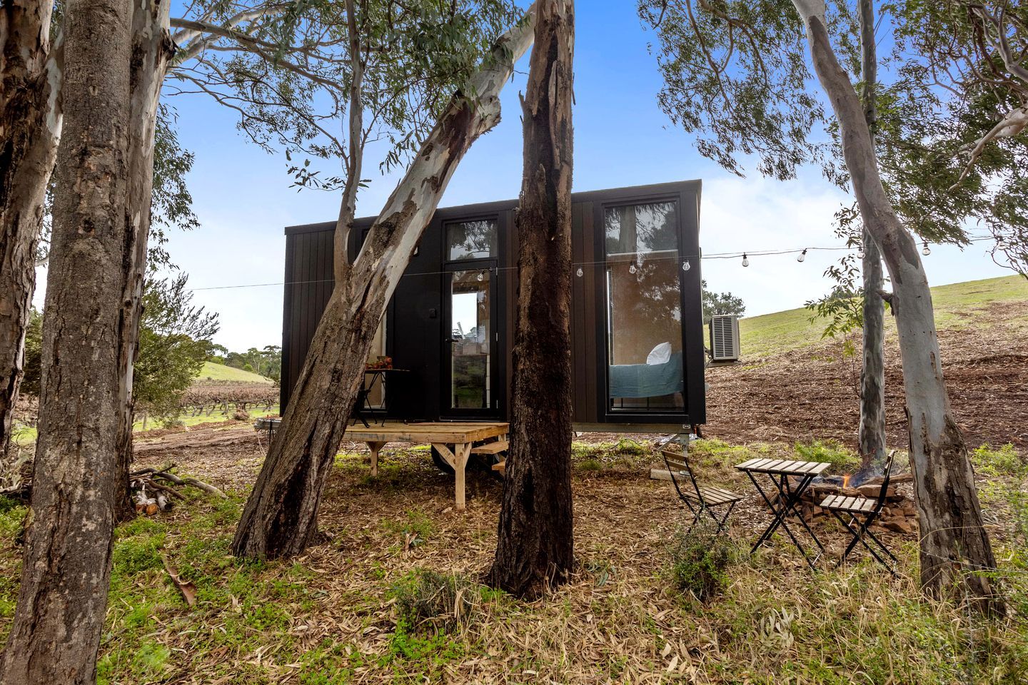 A modern treehouse with a wooden deck, a table, and a bench.