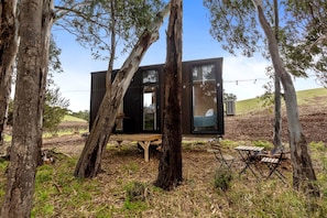 A modern treehouse with a wooden deck, a table, and a bench.