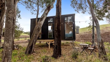 A modern treehouse with a wooden deck, a table, and a bench.