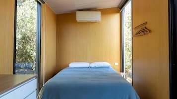 A narrow room with a bed, wooden walls, and a window.