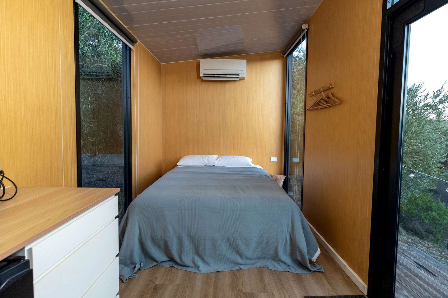 Une chambre à coucher avec un lit, des murs en bois, une fenêtre et un appareil de climatisation.