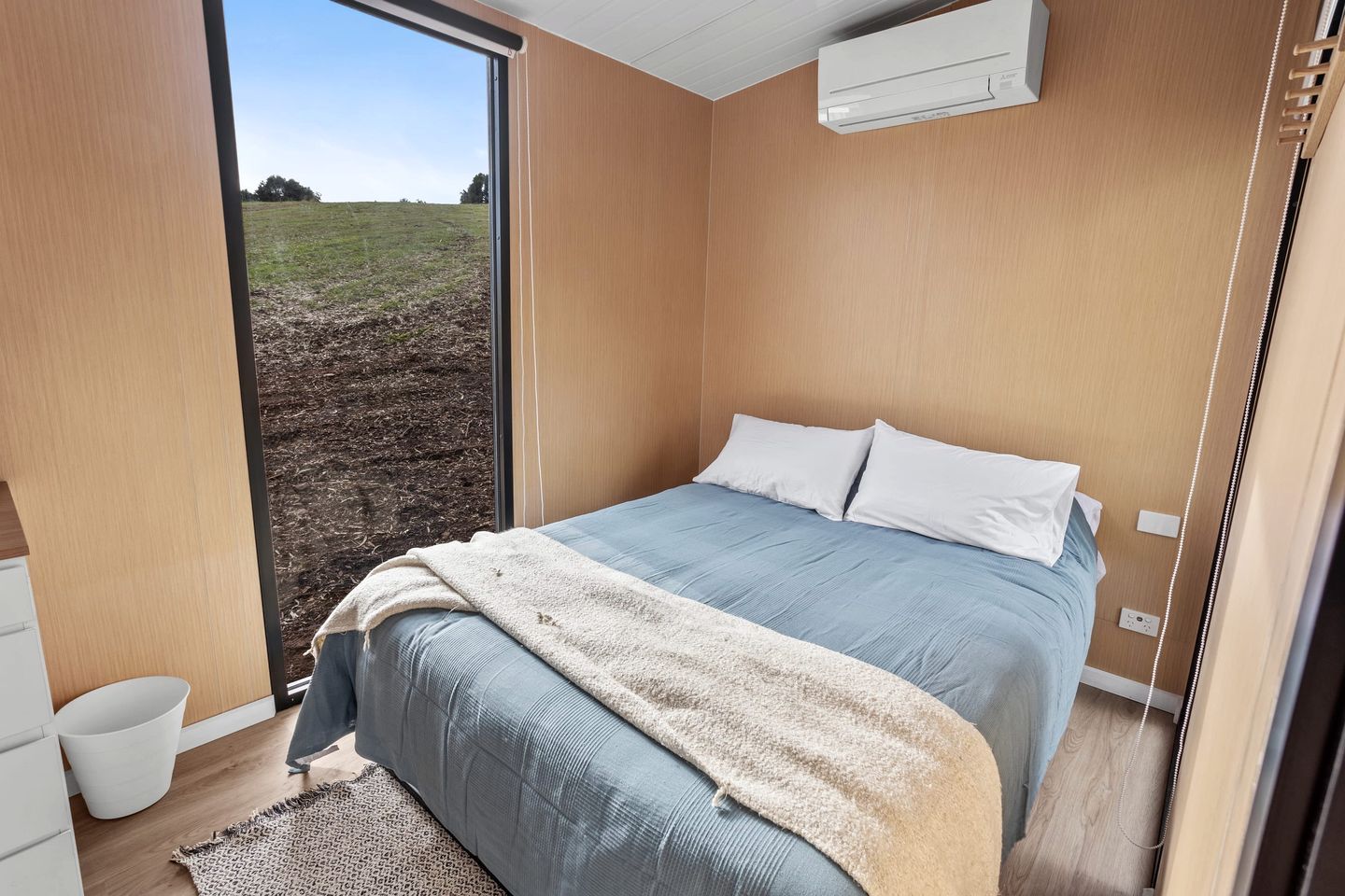 A bedroom with a bed, a window, and an air conditioning unit.