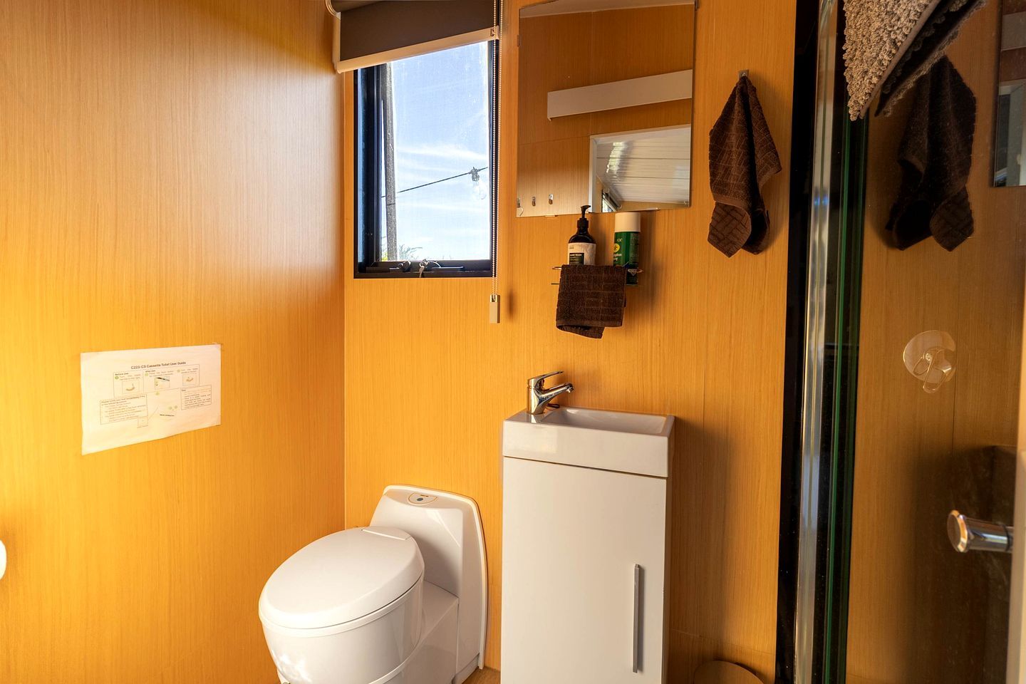 A compact bathroom with a toilet, sink, and a small window.