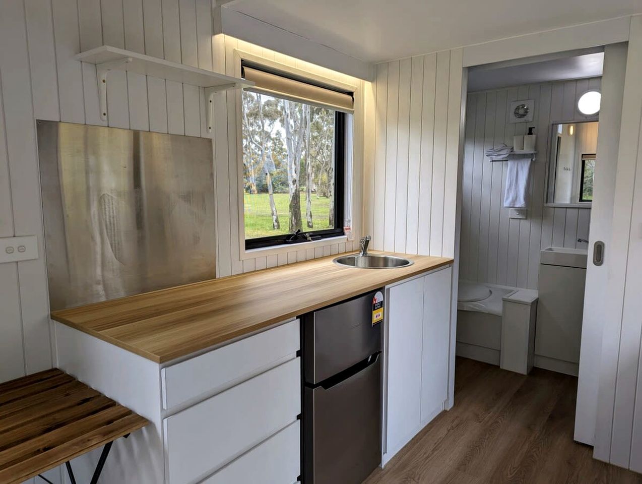 Una cocina compacta con encimera de madera, un lavaplatos integrado y un refrigerador.