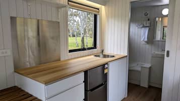 Una cocina compacta con encimera de madera, un lavaplatos integrado y un refrigerador.