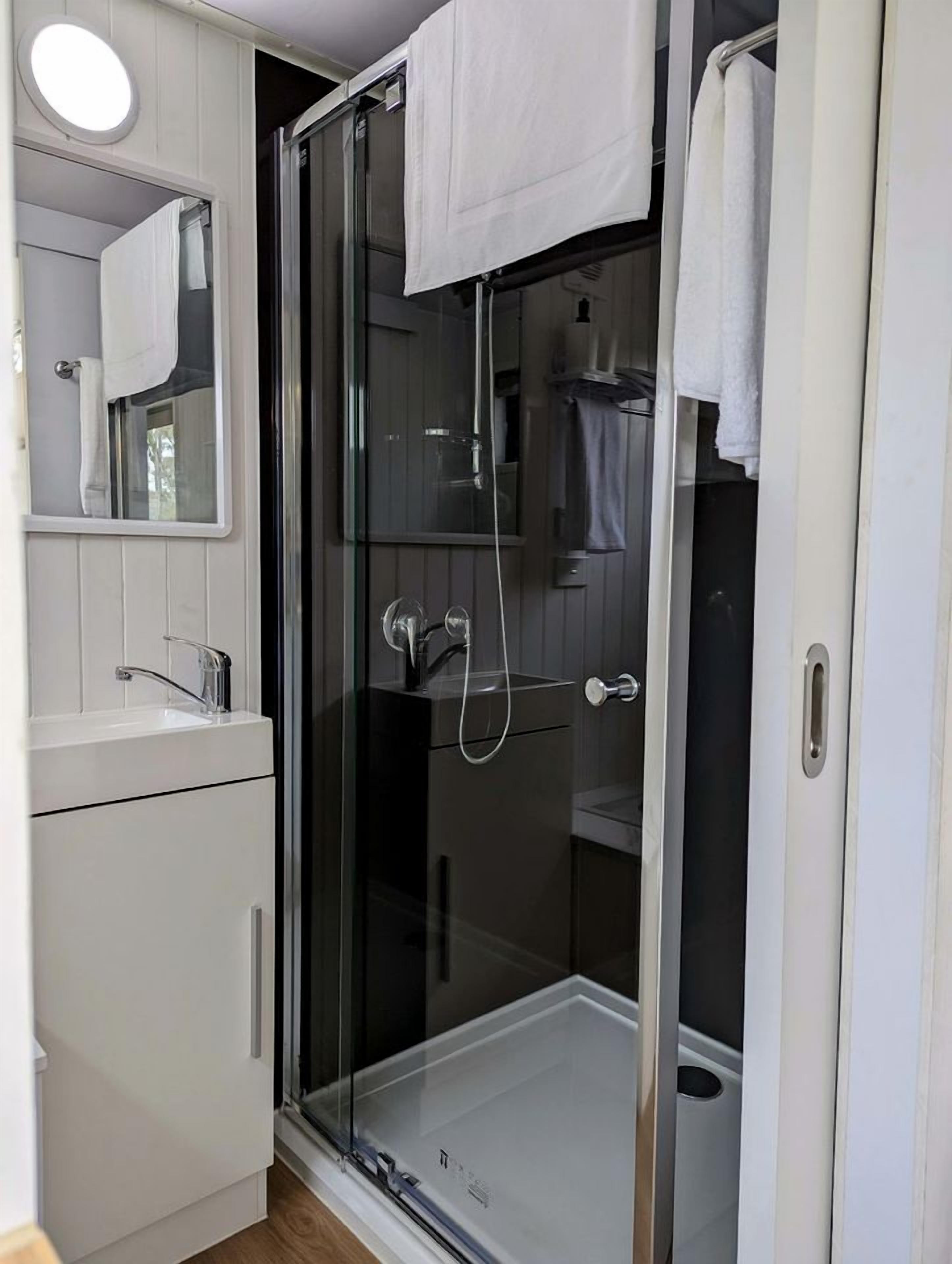 Une salle de bain avec une douche à parois de verre, un lavabo blanc et un miroir au-dessus du lavabo.