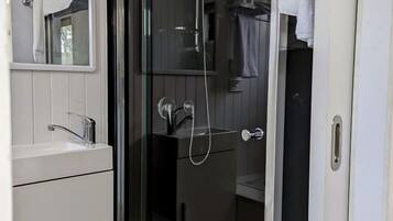 Une salle de bain avec une douche à parois de verre, un lavabo blanc et un miroir au-dessus du lavabo.