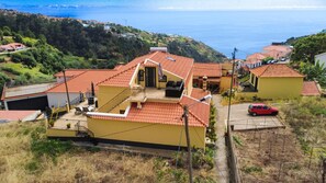 Un bâtiment jaune avec un toit recouvert de tuiles rouges, un balcon et une vue sur la mer.