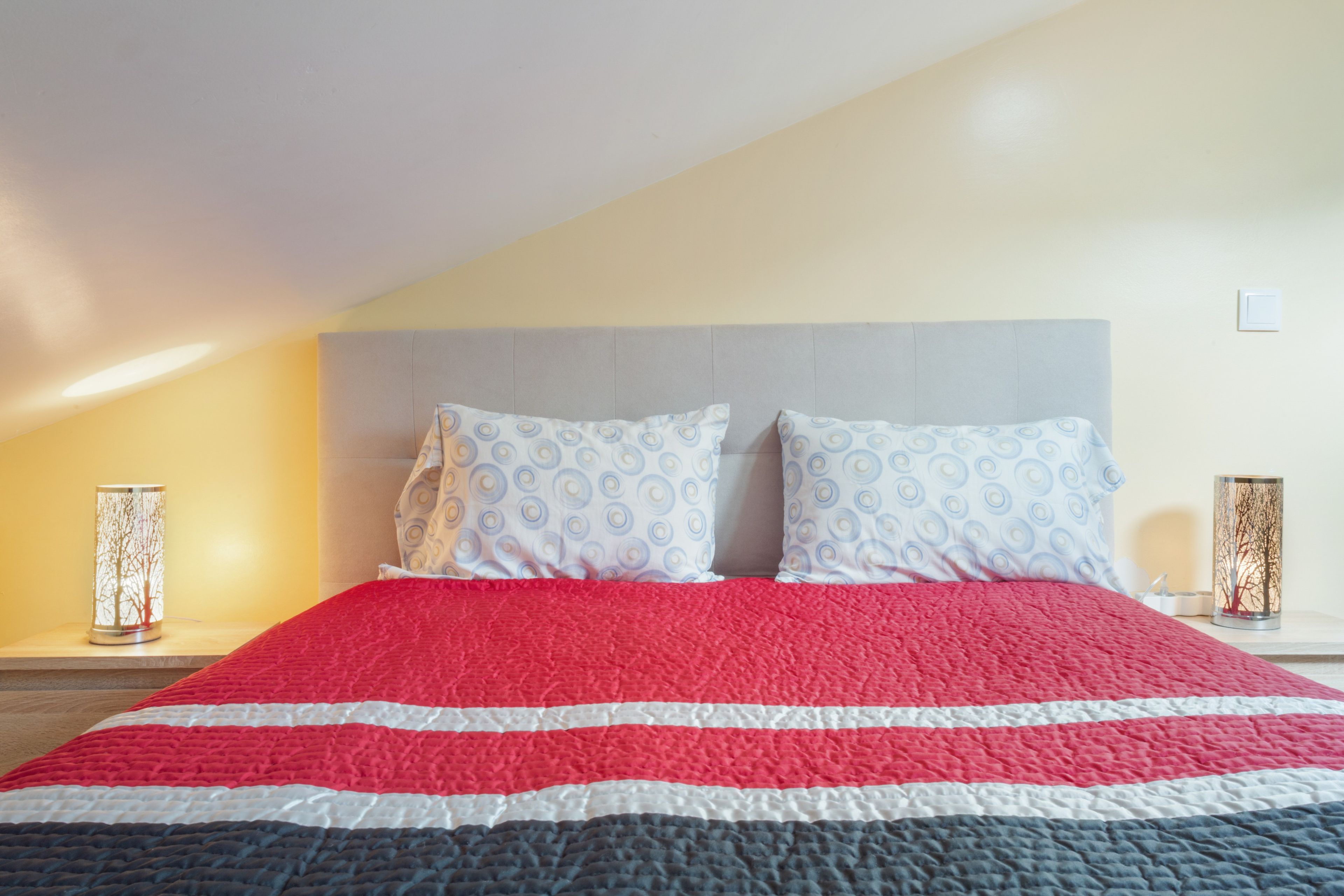 Een slaapkamer met een bed, twee kussens, een nachtkastje en een nachttafel.