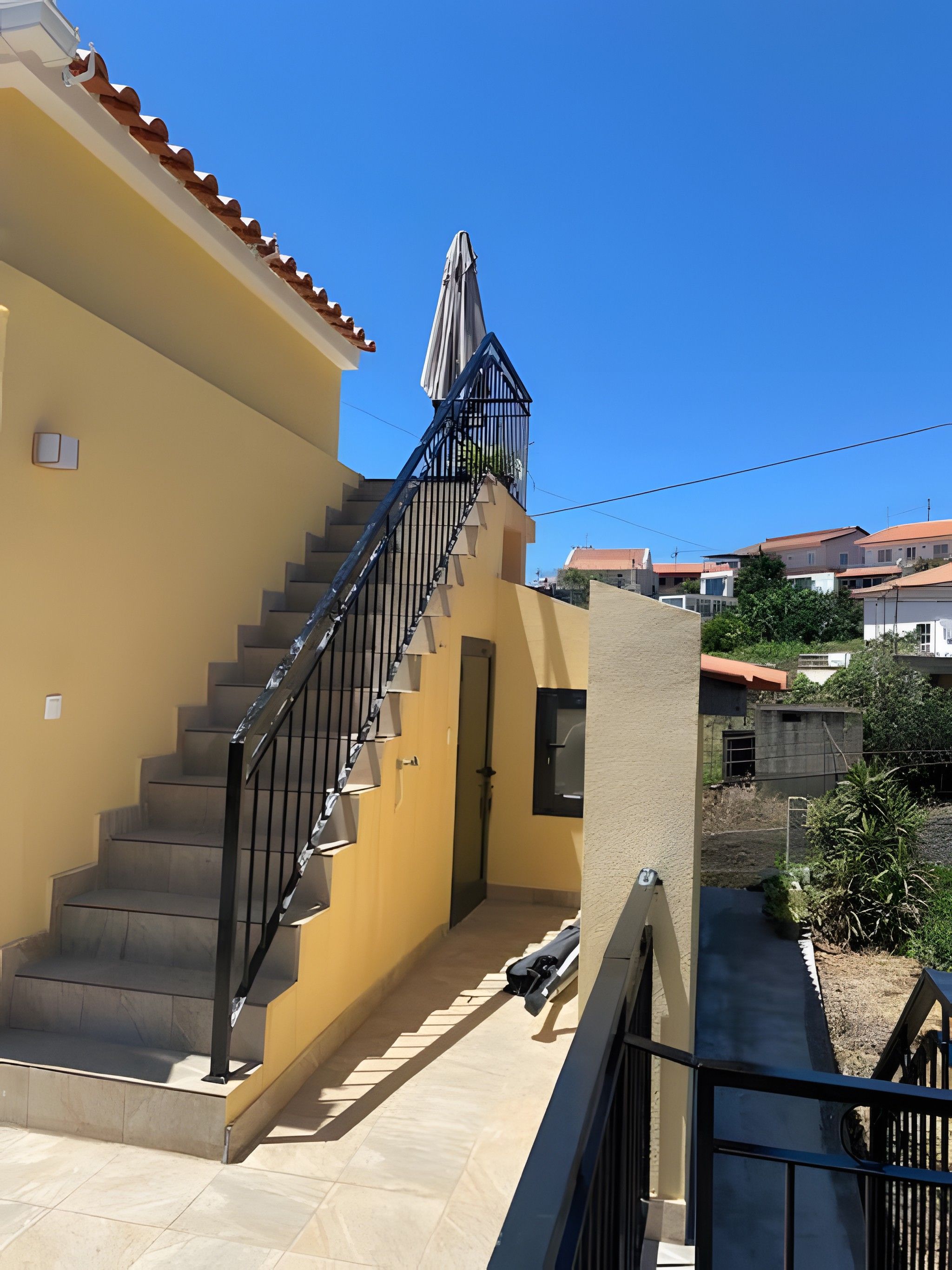 Ein Wohngebäude mit Treppe, einer Tür und einem kleinen Balkon mit Geländer.