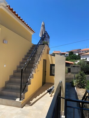 Un immeuble résidentiel doté d’un escalier, d’une porte et d’un petit balcon avec une balustrade.