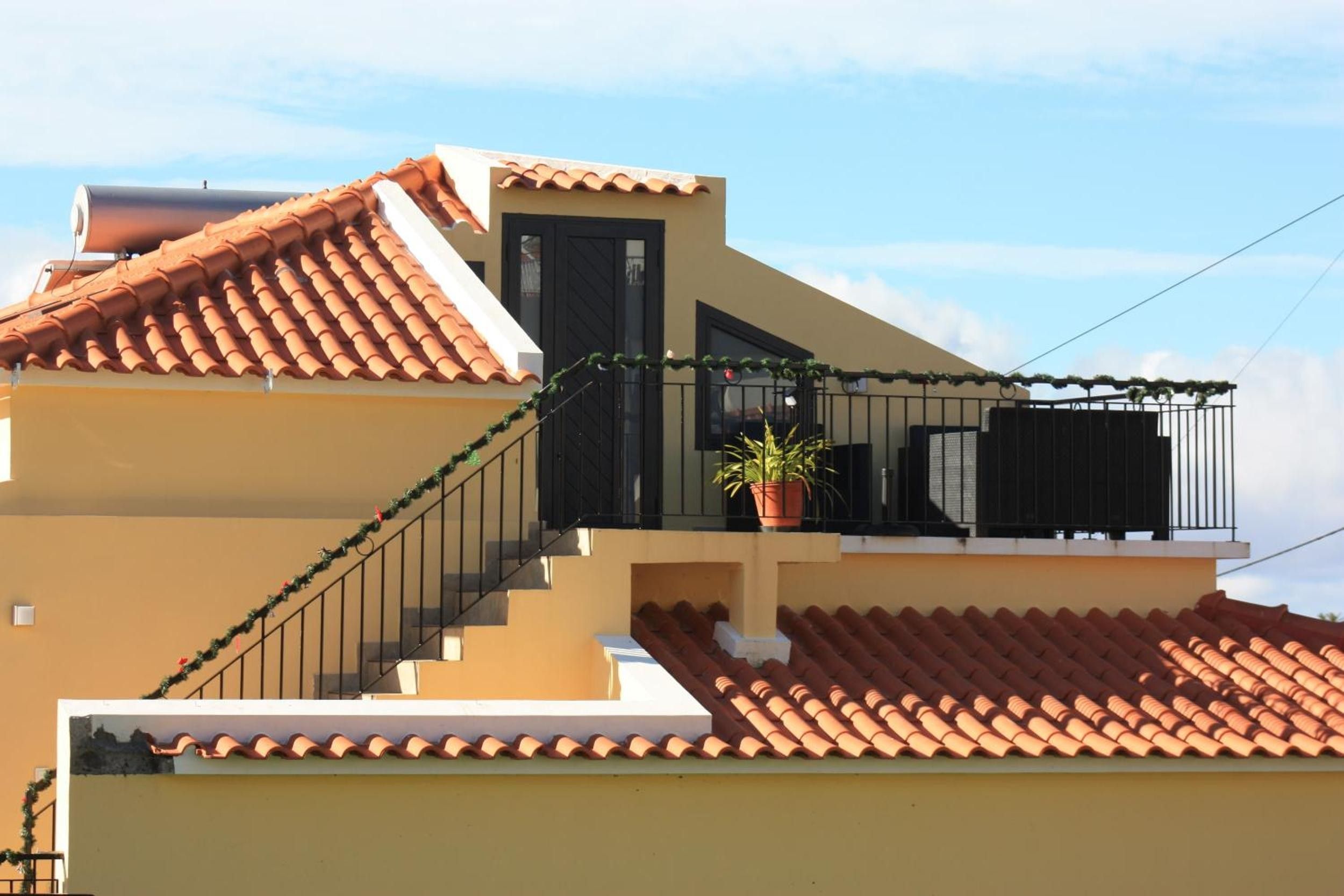 Ein zweistöckiges Gebäude mit einem Ziegeldach, einem Balkon mit einem Blumentopf und einer Treppe.