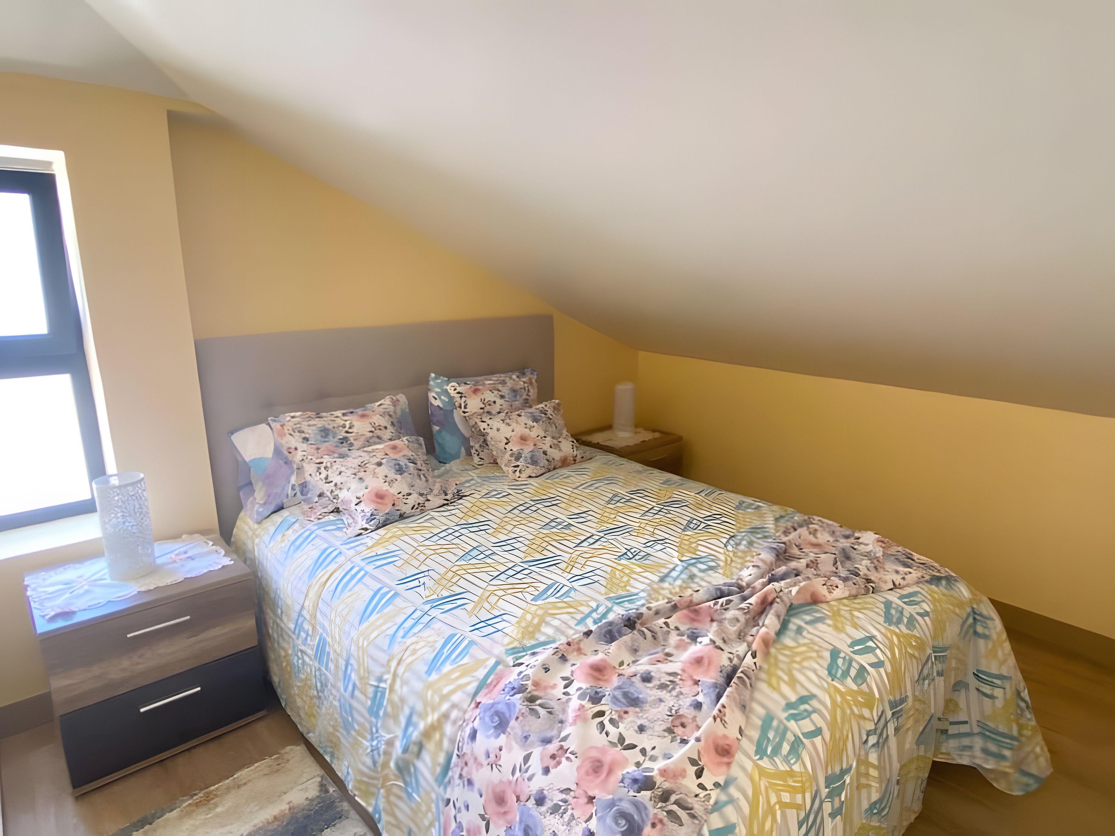 Un dormitorio con cama, mesita de noche y ventana.