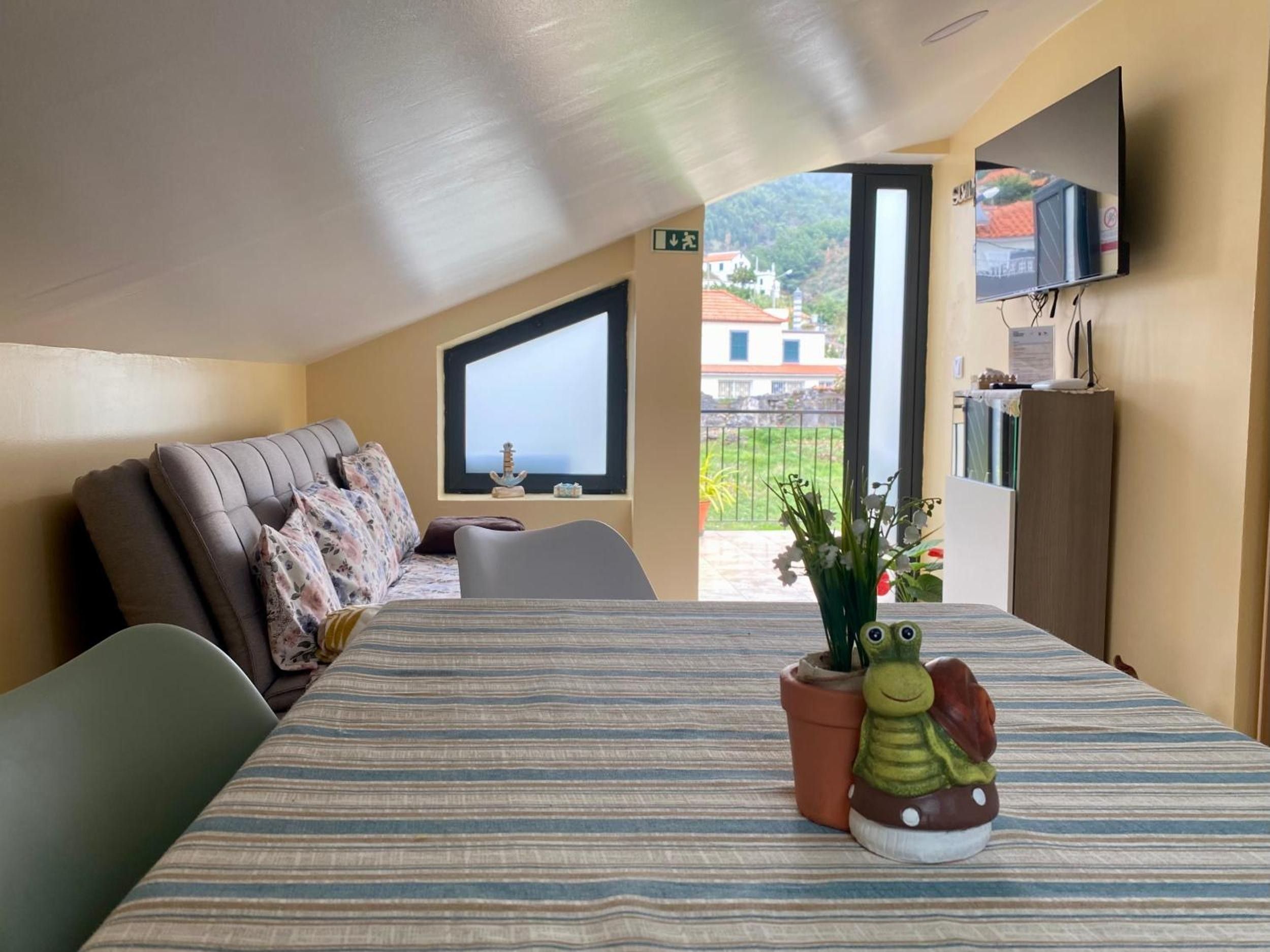 Una habitación con cama, sofá, televisión y ventana con vistas a edificios.