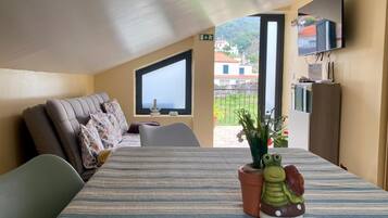 Una habitación con cama, sofá, televisión y ventana con vistas a edificios.