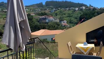 Ein Balkon mit Blick auf eine Hügellandschaft, ein Tisch mit einem Stuhl und ein Blumentopf.