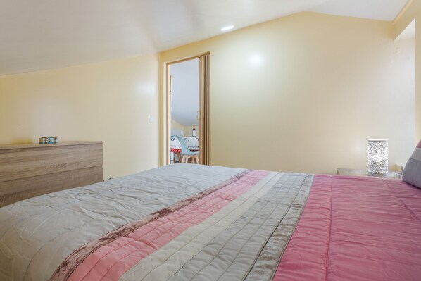 A bedroom with a bed, a dresser, a mirror, and a nightstand.
