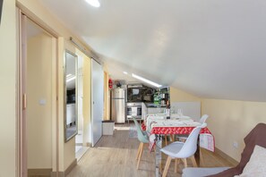 A compact kitchen with modern appliances, a dining area with a table set for two, and a cozy living space with a sofa.