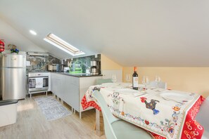 Cuina compacta amb zona de menjador, equipada amb nevera, forn i cafetera.