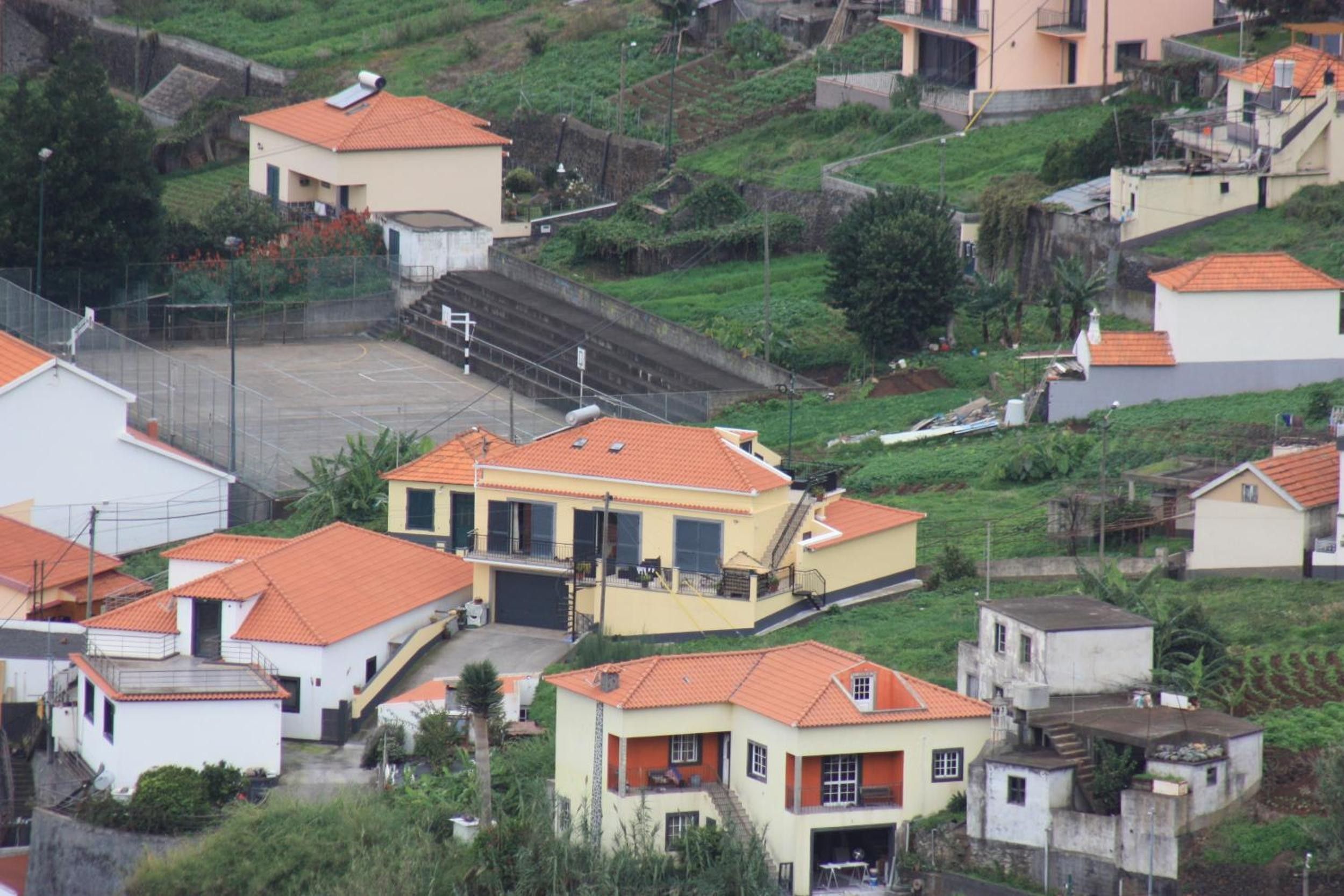 Zona residencial com casas de telhado vermelho e um edifício central com garagem e escadaria.