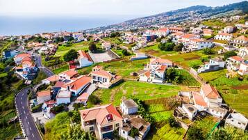 Uma vila costeira com casas em terraços, uma estrada principal e vista para o mar.