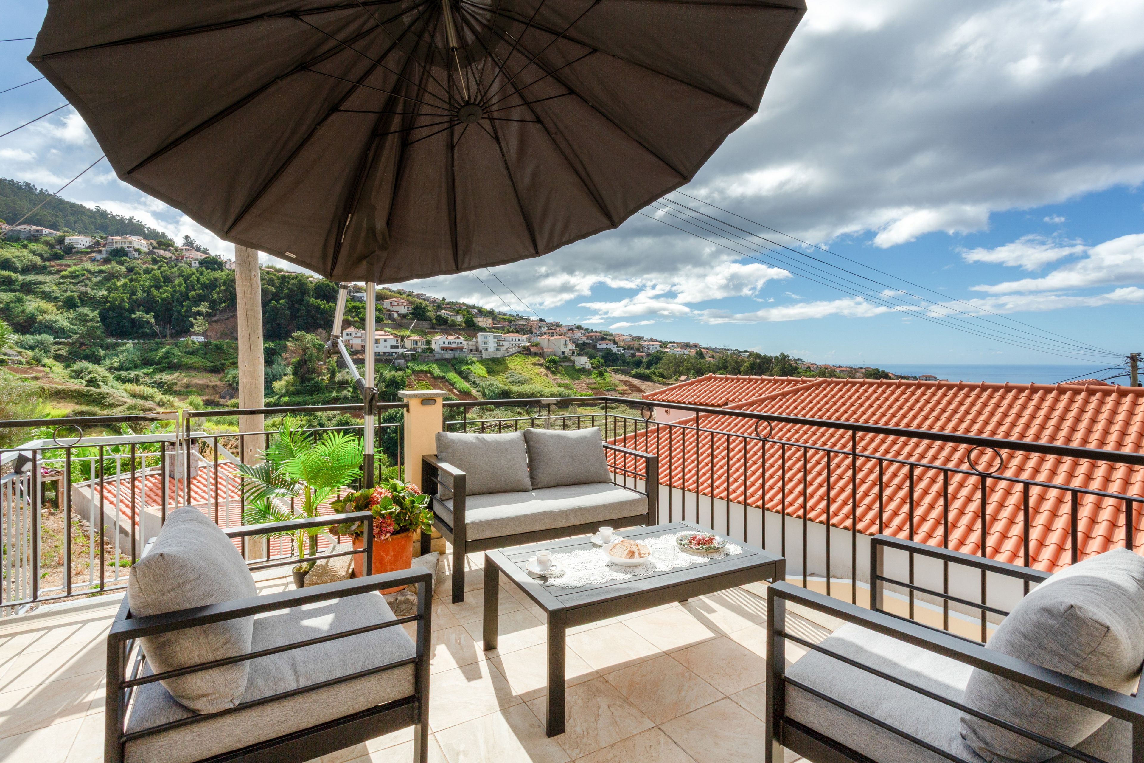 Een balkon met een tafel, stoelen en een grote parasol.
