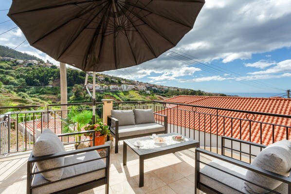 A balcony with a table, chairs, and a large umbrella.