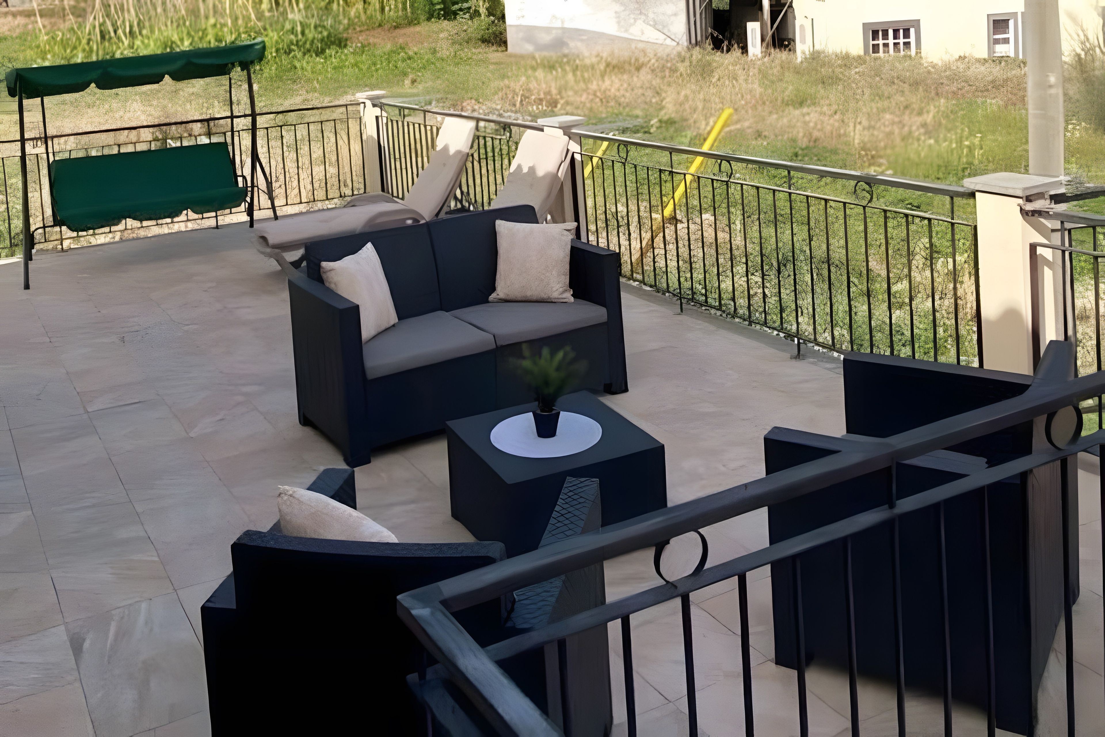 Uma área de estar externa com um sofá, uma mesa pequena e um toldo verde.