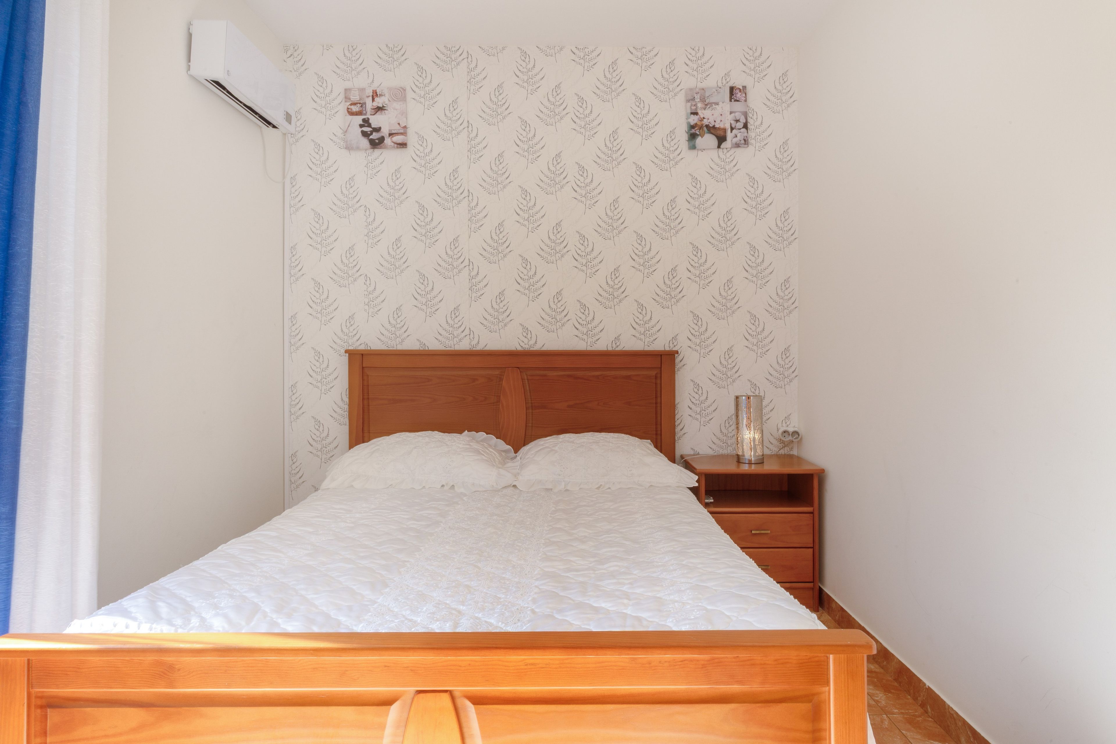 Een eenpersoonsbed met houten hoofdbord in een kamer met behang met patroon.