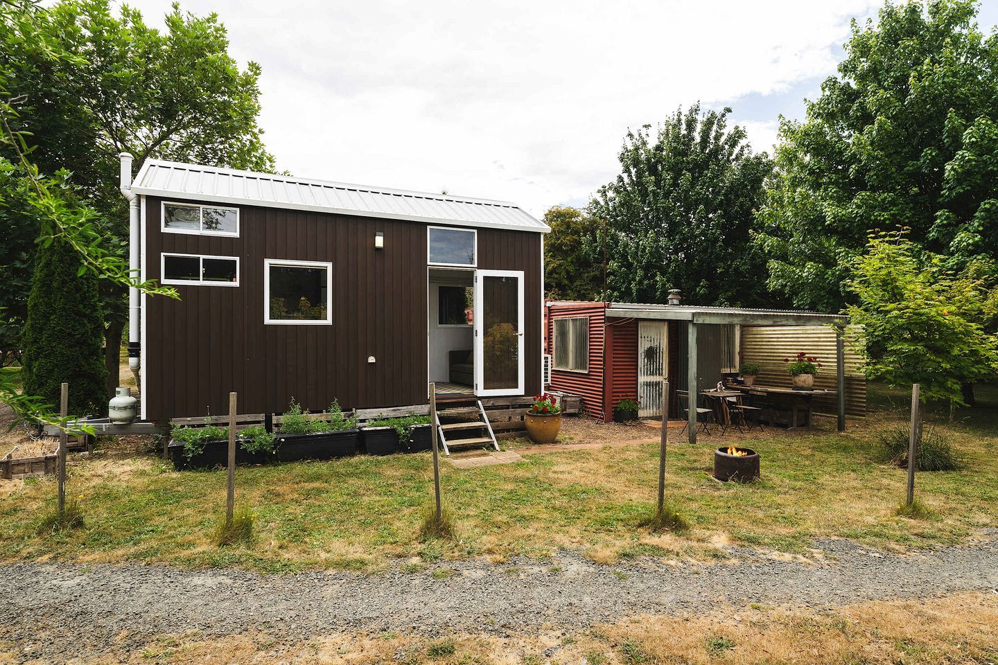 A compact house with a small porch and a fire pit in the yard.