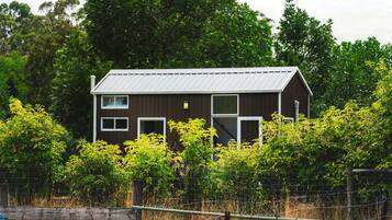 A two-story building with a metal roof, surrounded by dense greenery and a wire fence.