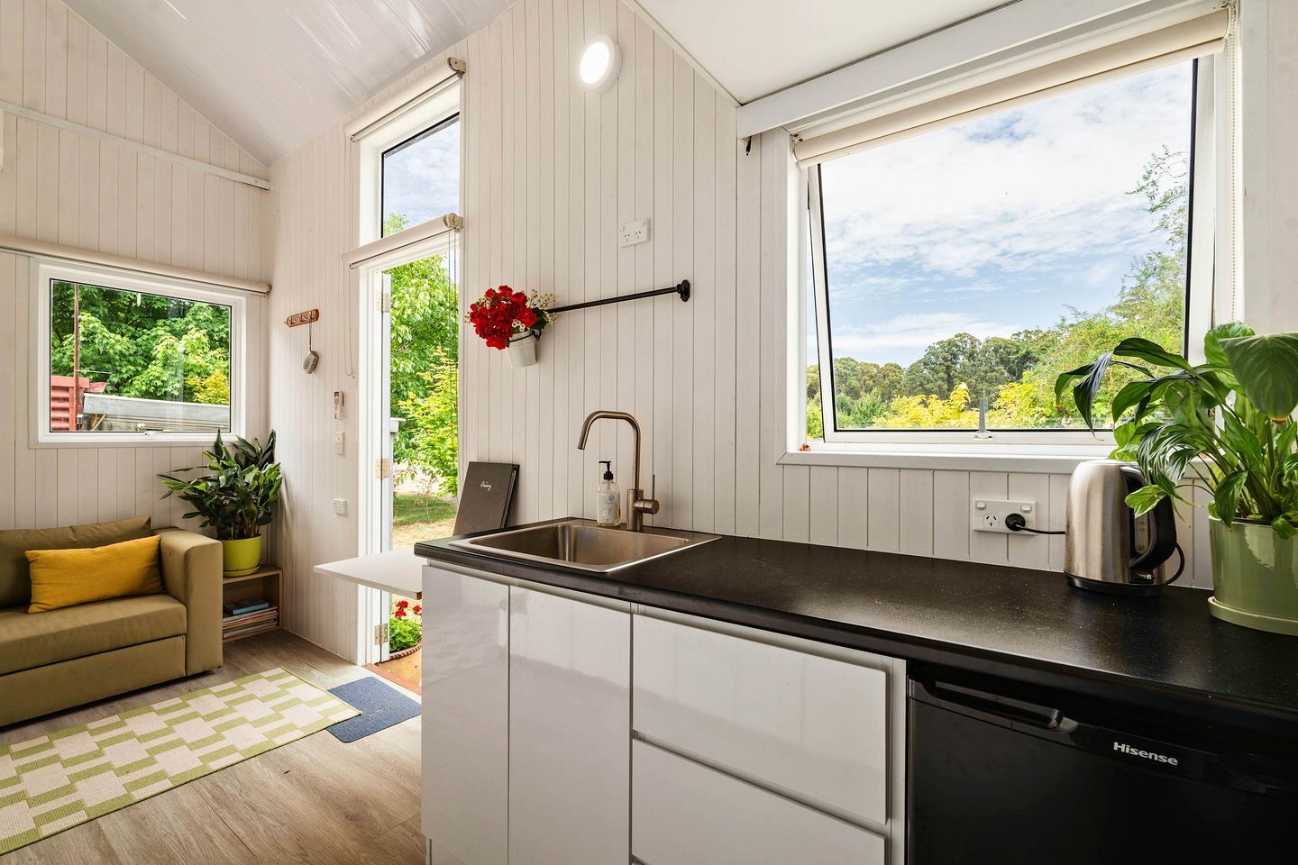 Cocina compacta con pileta, mostrador y vista a la vegetación.