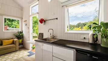 Cocina compacta con pileta, mostrador y vista a la vegetación.