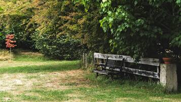 A park bench with a concrete support, surrounded by grass and trees.