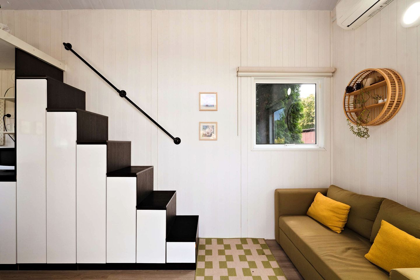A modern interior with a staircase, a sofa, and a window with a view.