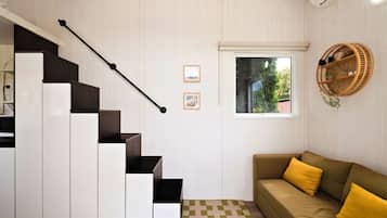 A modern interior with a staircase, a sofa, and a window with a view.