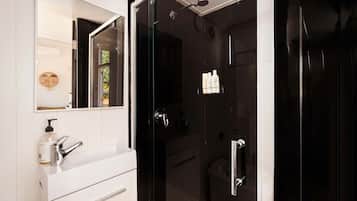 A modern bathroom with a white vanity, a glass shower enclosure, and a mirror with a wooden-framed inset.