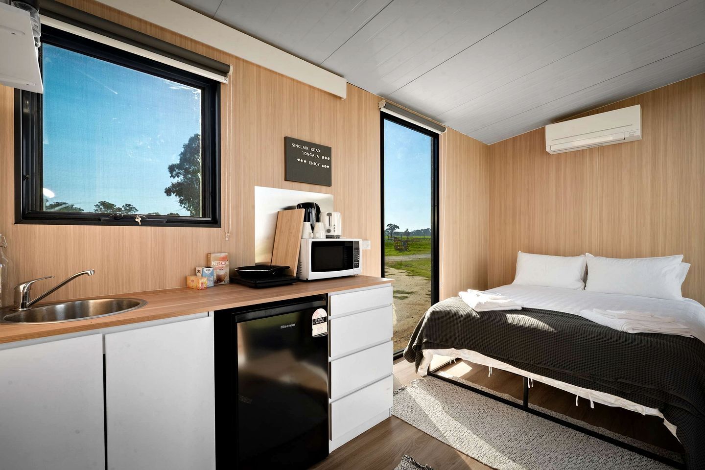 A modern bedroom with a bed, a bedside table, a window, and a view of the outdoors.