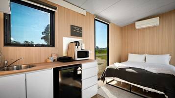 A modern bedroom with a bed, a bedside table, a window, and a view of the outdoors.