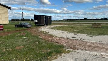 A rural setting with a trailer, a car, and a building.